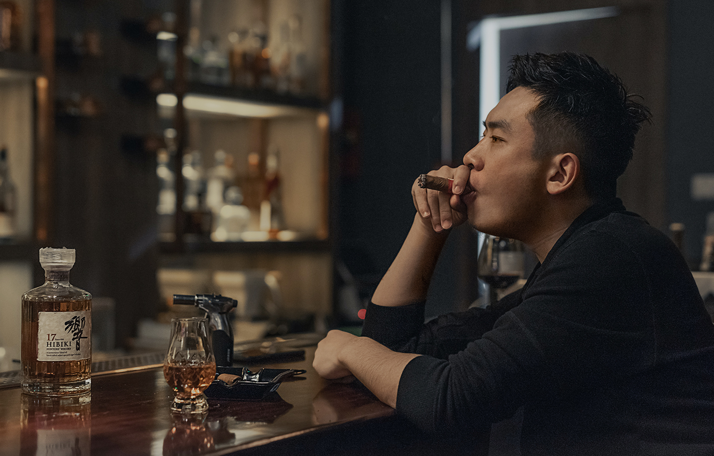 bearded guy smoke a cigar holds glass